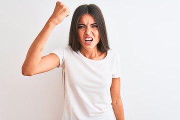 Poster - Young beautiful woman wearing casual t-shirt standing over isolated white background angry and mad raising fist frustrated and furious while shouting with anger. Rage and aggressive concept.