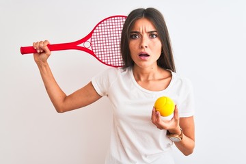 Canvas Print - Beautiful sportswoman playing tennis using racket standing over isolated white background scared in shock with a surprise face, afraid and excited with fear expression