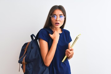 Wall Mural - Young student woman wearing backpack glasses holding book over isolated white background scared in shock with a surprise face, afraid and excited with fear expression