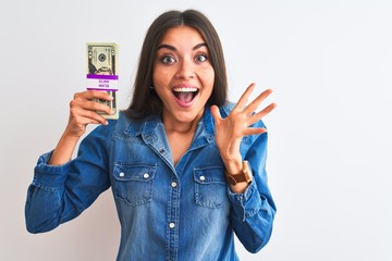 Poster - Young beautiful woman holding dollars standing over isolated white background very happy and excited, winner expression celebrating victory screaming with big smile and raised hands