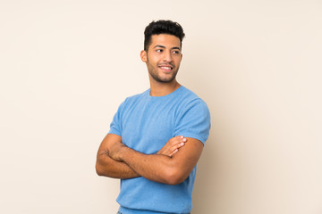Wall Mural - Young handsome man over isolated background with arms crossed and happy