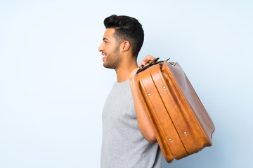 Wall Mural - Young handsome man over isolated background holding a vintage briefcase