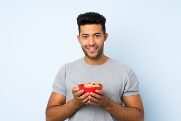 Wall Mural - Young handsome man over isolated background holding a bowl of cereals