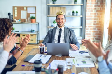 Group of business workers smiling happy and confident. Working together with smile on face applauding one of them wearing king crown at the office