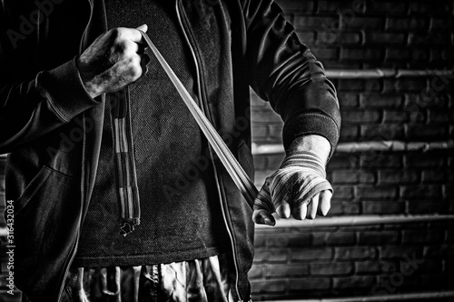 фотографія Young boxer preparing for fight, wrapping hands with bandage, copy space