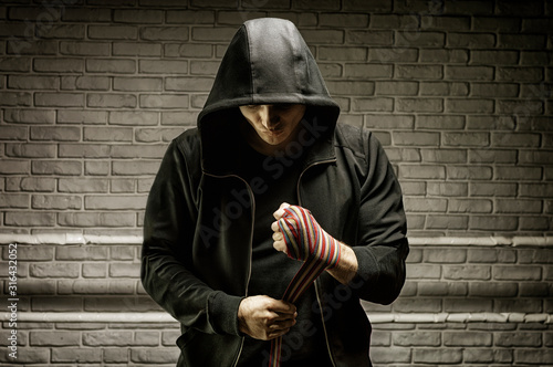 Young boxer preparing for fight, wrapping hands with bandage, copy space Фотошпалери