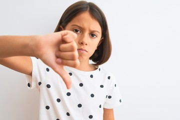 Wall Mural - Young beautiful child girl wearing casual t-shirt standing over isolated white background with angry face, negative sign showing dislike with thumbs down, rejection concept