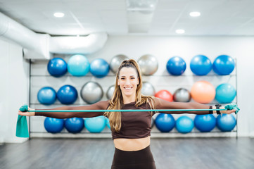 Beautiful woman in gym performing exercises with elastic bands.