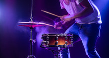 A Drummer Plays Drums On A Blue Background. Beautiful Special Effects Of Light And Smoke. The Process Of Playing A Musical Instrument.