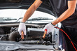 © phoderstock - Close up of man hand charging a car battery using electricity trough jumper cables.
