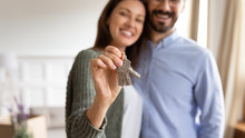 Smiling young couple show house keys moving in together