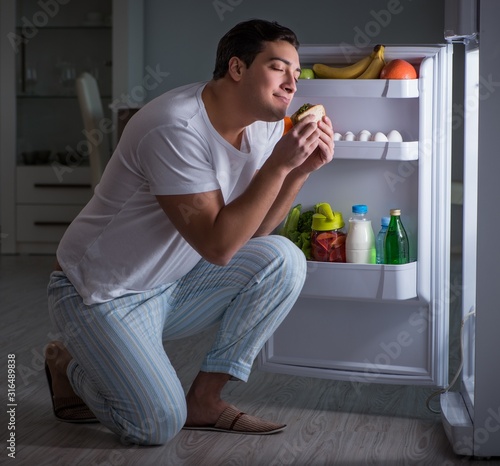 Cuadros en Lienzo Man at the fridge eating at night