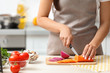 © New Africa - Young woman cutting vegetables for soup at table in kitchen, closeup