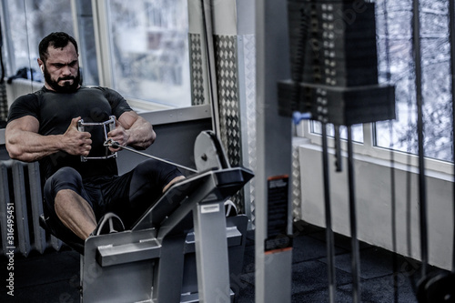 Cuadros en Lienzo powerful young athlete man with beard pulling heavy weight sitting in sport fitn