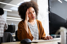 Overworked And Frustrated Young Woman In Front Of Computer In Office