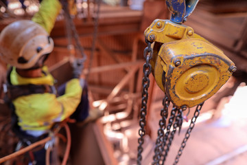 Wall Mural - Defocused of rope access rigger wearing harness safety helmet heavy duty glove abseiling working in fall arrest position commencing lifting a heavy load with clear chain block in the foreground 