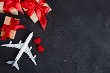 Holiday Travel Planning. Travel Concept. Airplane Model, Gift Boxes And Red Hearts On Dark Background.