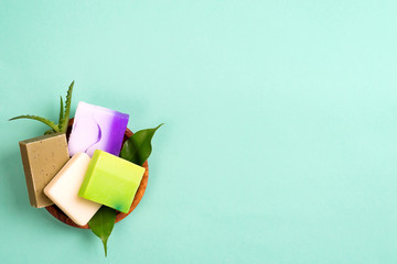 Handmade organic colorful homemade bar soaps in basket with leaves on green, copy space