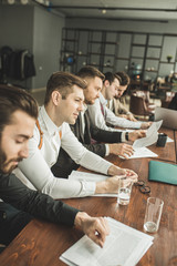 Wall Mural - young caucasian business people in formal wear keeping records on papers, making notes and discuss, isolated in modern boardroom