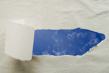 A Fragment Of Blue Sky In A Hole Of Torn Paper. Copy Space.