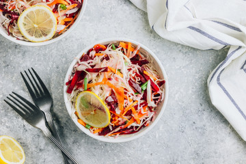 Wall Mural - Spring healthy vegan salad with raw beet, carrot and cabbage in white bowls. Alkaline Diet concept. Top view. Flat lay