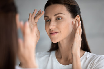 Close up beautiful woman with perfect skin looking in mirror