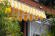yellow and white striped awning of shop in garden.