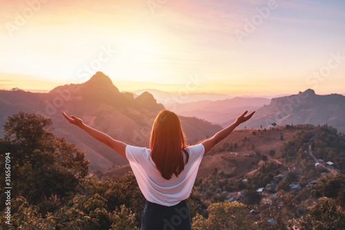 Cuadros en Lienzo Young woman traveler looking at sunset over the mountain