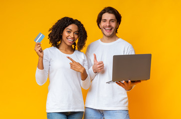 Wall Mural - Portrait of interracial couple with laptop and credit card in hands