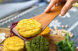 Vegan chickpea burgers cutlets or patties. Healthy vegan diet food. Woman hands holds mixed vegetables yellow pumpkin, orange carrot, green spinach and red beet bean cutlets with wooden spatula