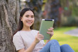 © Suriyo - Beauty women using tablet reading E-book sitting in city park morning fresh