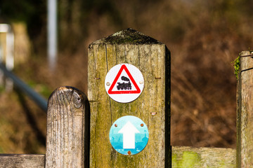 Bradford on Avon wooden post with small circle sign badges, an arrow on a blue background with local silhouettes and a steam train in a red triangle