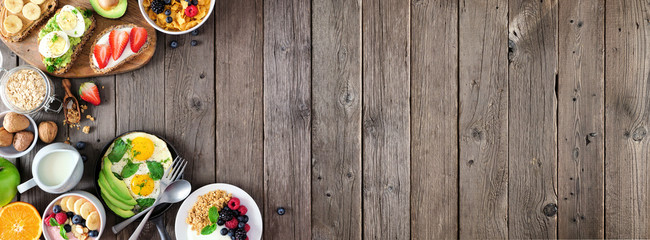 Wall Mural - Healthy breakfast food banner with side border. Table scene with fruit, yogurt, smoothie bowl, nutritious toasts, cereal and egg skillet. Top view over a rustic wood background. Copy space.