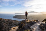 Fototapeta Tęcza - Beautiful woman standing on a cliff during sunset with the mediterranean sea in the background at Cap de Creus