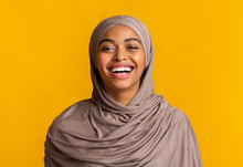 Portrait Of Sincerely Laughing Black Muslim Woman Over Yellow Background