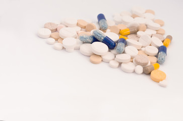 Heap of colorful pills in the shape of a heart, tablets and capsules on white background. Drug prescription for treatment medication health care concept, top view with copy space.