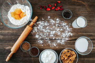 Bakery preparation in kitchen, dough recipe ingredients and rolling pin on vintage wood table from above.