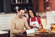 © Mediteraneo - Beautiful young couple is using a digital tablet and smiling while cooking in kitchen at home