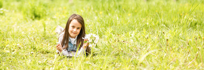 Wall Mural - Portrait of cute and pretty little girl in spring blooming trees. Adorable little girl smiling in blooming garden on sunny day. Child and flowers. Childhood & natural tenderness. Children's day.