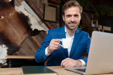 Wall Mural - Positive businessman smiling and holding a cup of coffee