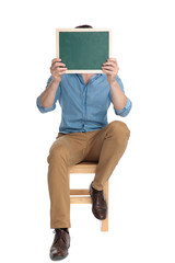 Poster - young casual man hiding face behind green board