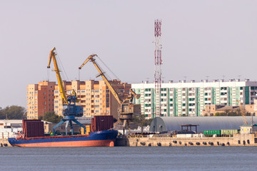 Industrial landscape with port cranes in the port on the background of the city view