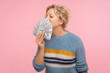 Portrait of pleased happy woman with curly hair in warm sweater smelling dollar banknotes and closing eyes from pleasure and satisfaction, greed for money. studio shot isolated on pink background