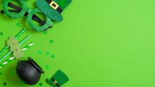 St Patricks Day Banner Design. Top View Pots Of Gold, Drinking Straws With Shamrock Four Leaf Clover, Leprechaun Hat And Patricks Day Glasses On Green Background. Saint Patrick's Day Greeting Card