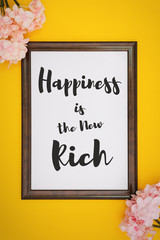 Wall Mural - Motivational and Inspirational Quotes. Happiness is The New Rich. Still Life of Word Frame Against Yellow Background.