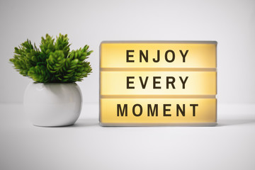 Wall Mural - Motivational and Inspirational Quotes. Enjoy Every Moment. Still Life of Lightbox on Work Desk.