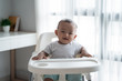 Cute baby sitting on high chair indoors
