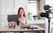 © weedezign - Asian young female blogger giveaway gift fan following channel while recording vlog video with makeup cosmetic at home online influencer concept.live streaming viral.mock up blackboard for your design