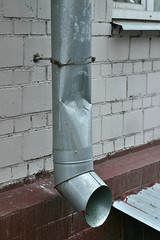 deformed drainpipe on the wall of the building