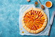Peach galette, pie, cake with cream on blue background. Top view. Copy space.